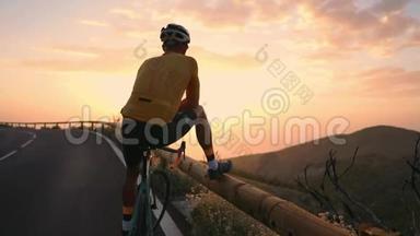 骑自行车的人穿着黄色的t恤在山上看日落。 健身后休息，<strong>钢铁侠</strong>